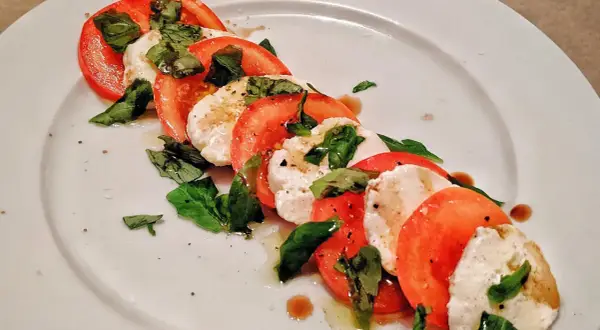 Caprese-sallad med skivade tomater, färsk mozzarella och basilika. Ett enkelt och gott mozzarella recept.