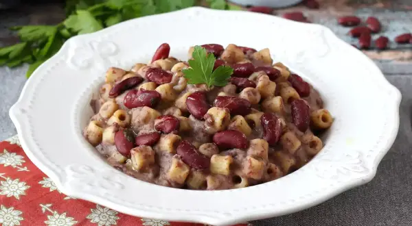 En skål med krämig pasta fagioli, toppad med färska bönor och persilja. Ett härligt recept för en mysig middag.
