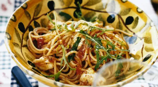En skål med spaghetti med tomatsås, toppad med ruccola och strödd med svartpeppar. En härlig pasta med tomatsås som ser utsökt ut.