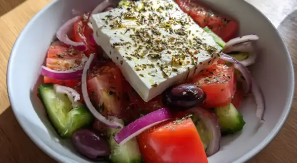 En fräsch grekisk sallad med fetaost, tomater, gurka, rödlök och oliver, toppad med örter.
