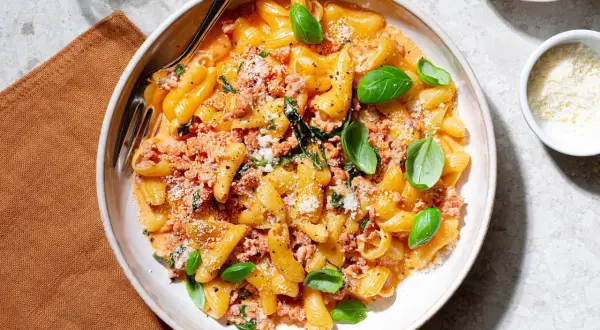 En skål med pasta alla norcina, krämig och toppad med färsk basilika och riven parmesan.