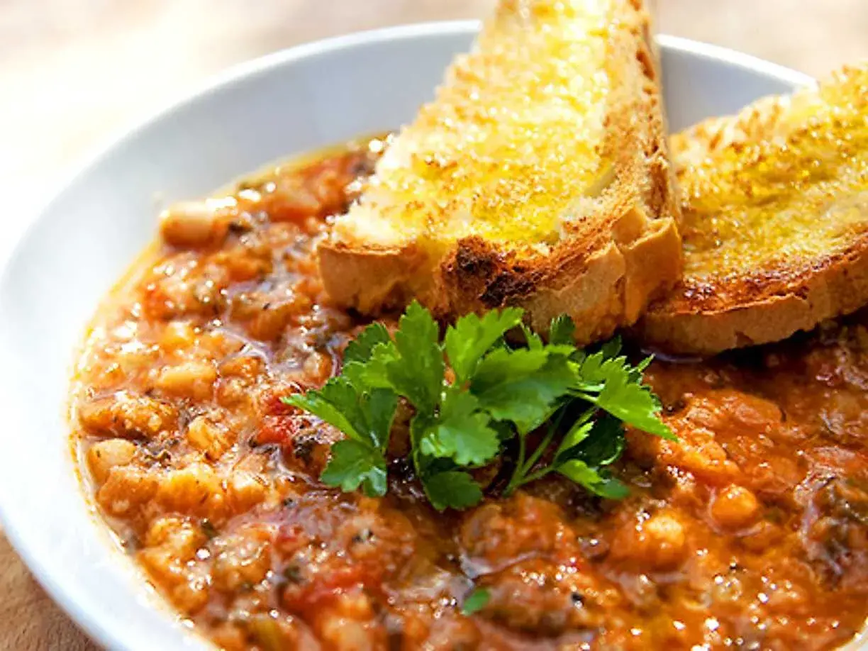 En närbild av en skål med mustig ribollita, toppad med rostat bröd och färsk persilja. Ett perfekt ribollita recept för en kall dag.
