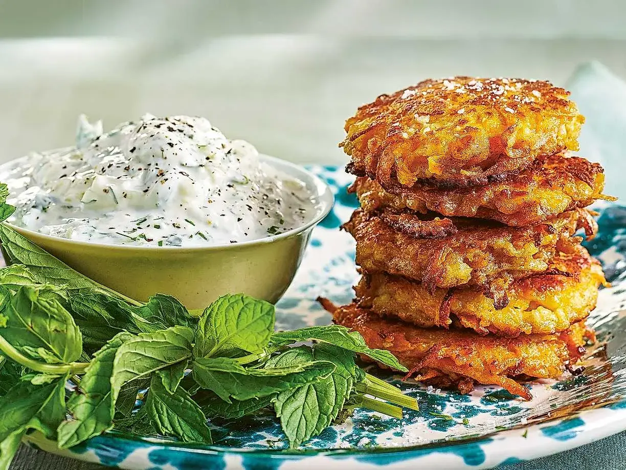 En stapel gyllene halloumi och morotsbiffar serveras med en krämig yoghurtsås och färsk mynta.