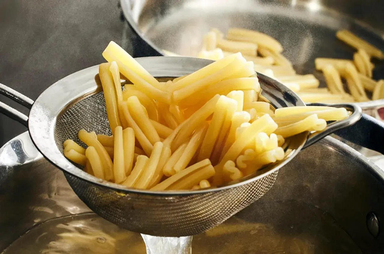Nyskördade durumvete pasta i ett durkslag, redo att serveras.