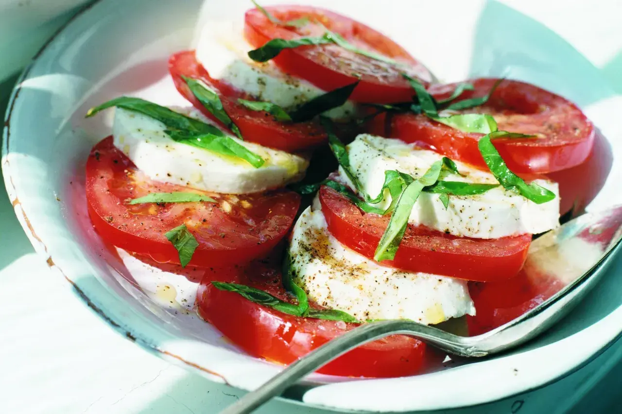 En klassisk napolitansk sallad med skivade tomater, färsk mozzarella och basilika, strödd med peppar. Enkel och fräsch.