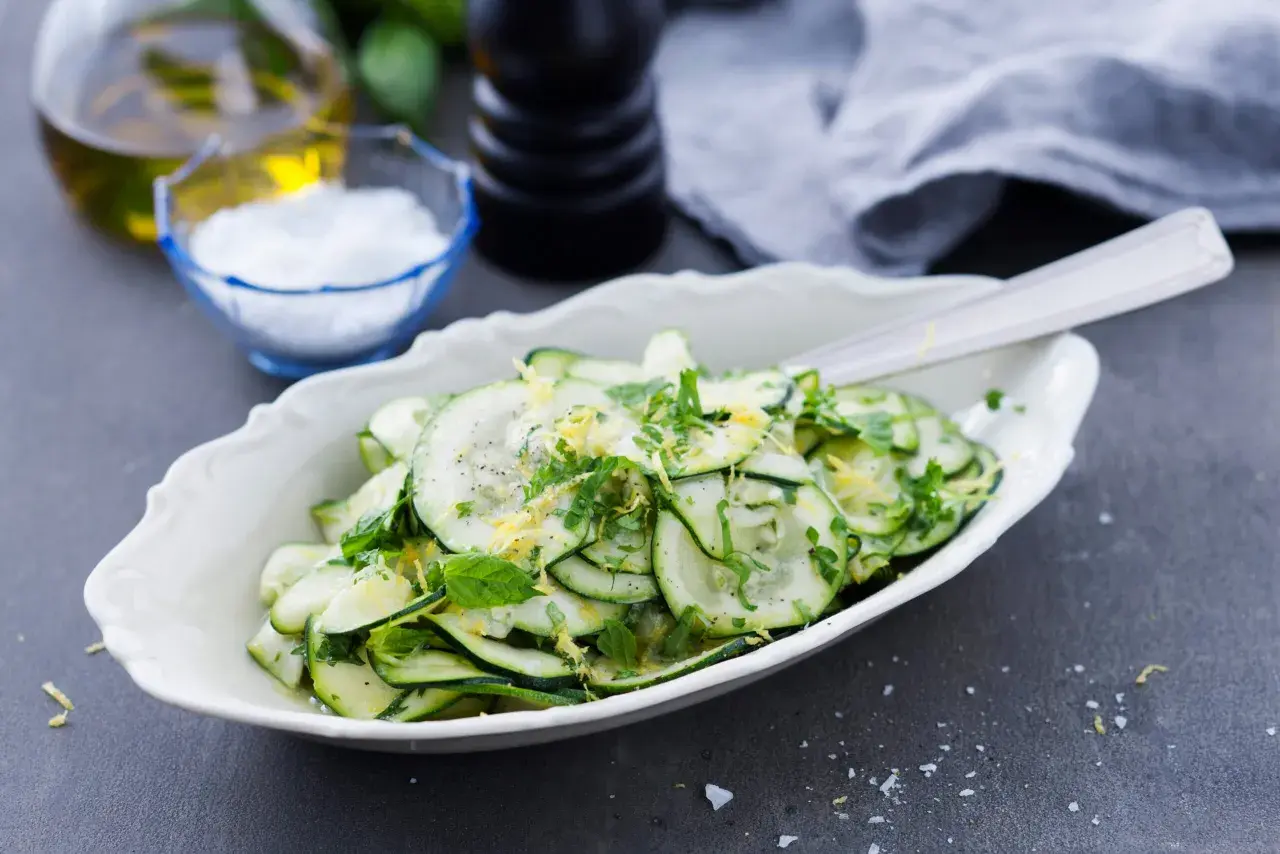 En fräsch zucchini sallad med citronzest och örter, serverad i en vit skål.