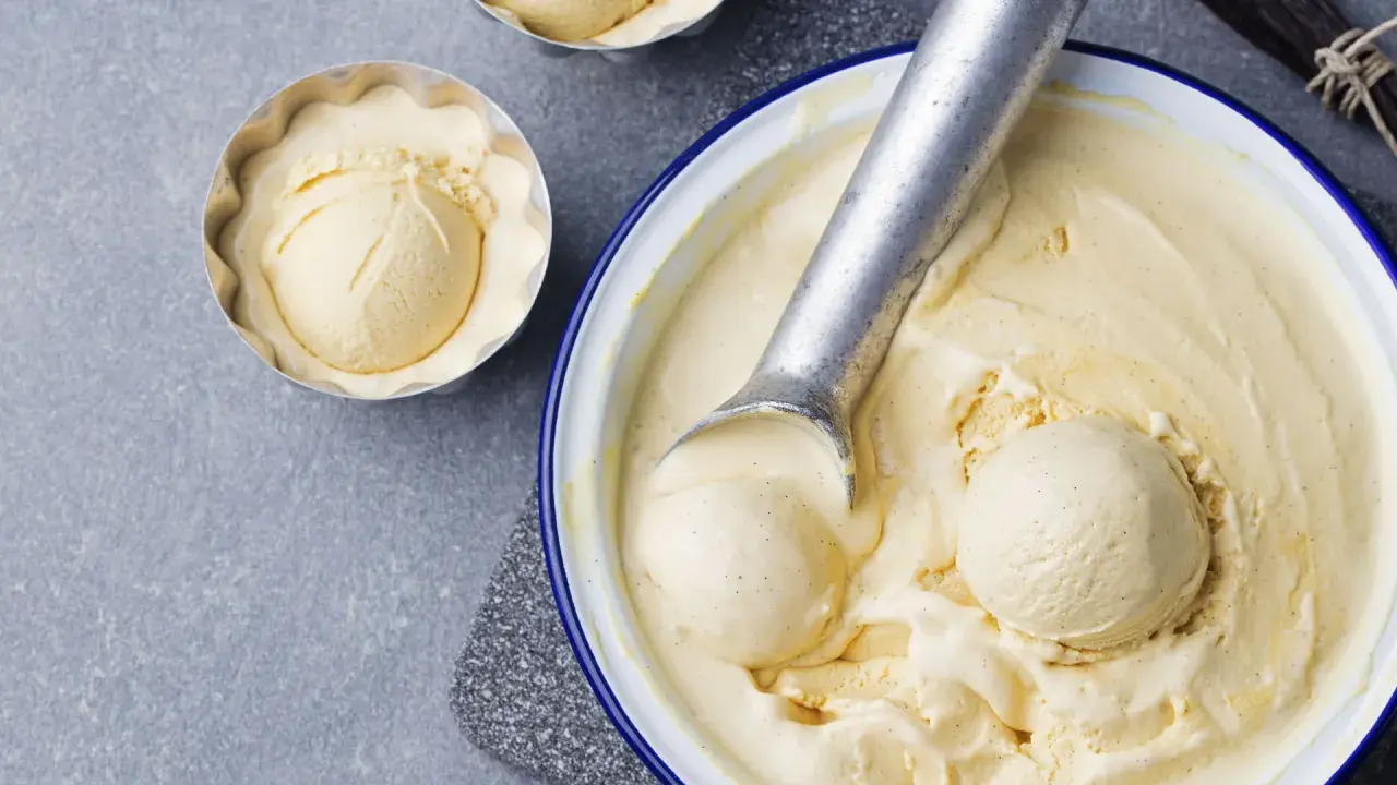 Krämig vaniljglass, perfekt för ett enkelt gelato recept. En skopa glass i en form och en stor skål med glass och skopa.