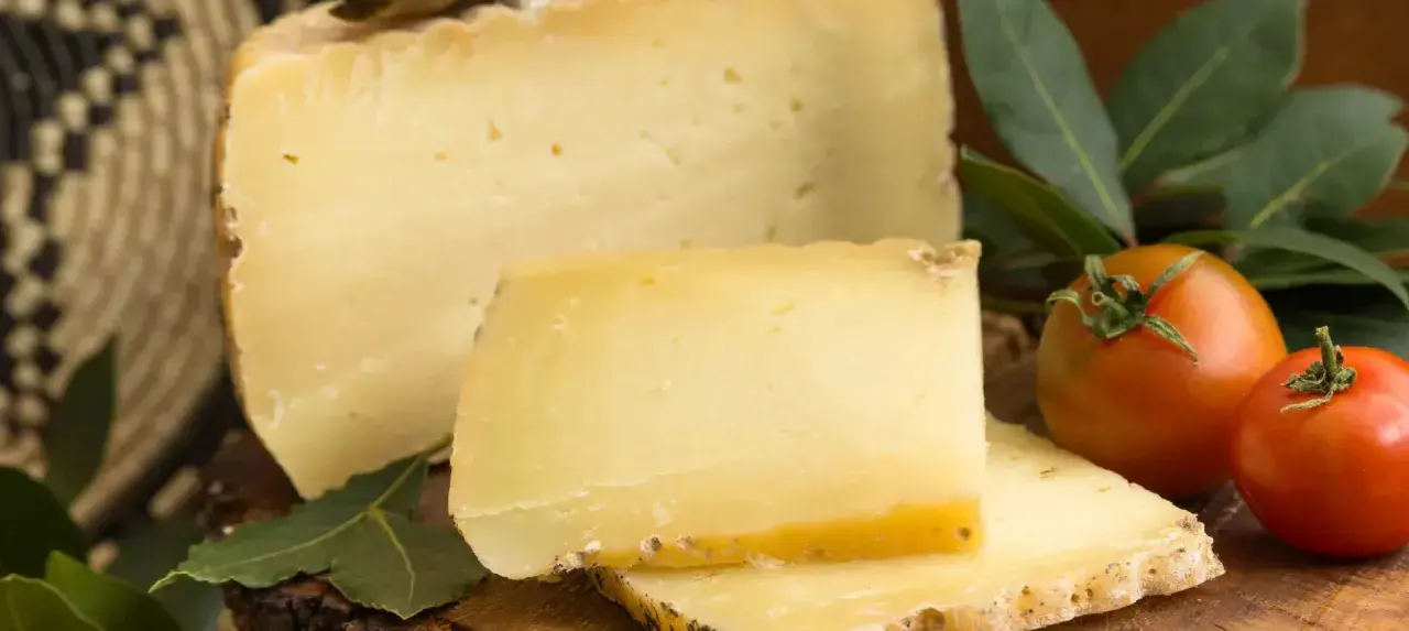 En bit pecorino ost med tomater och gröna blad.