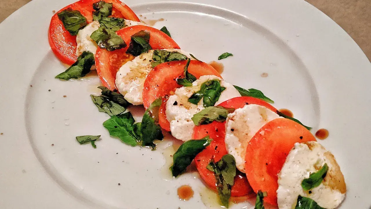 Caprese-sallad med skivade tomater, färsk mozzarella och basilika. Ett enkelt och gott mozzarella recept.