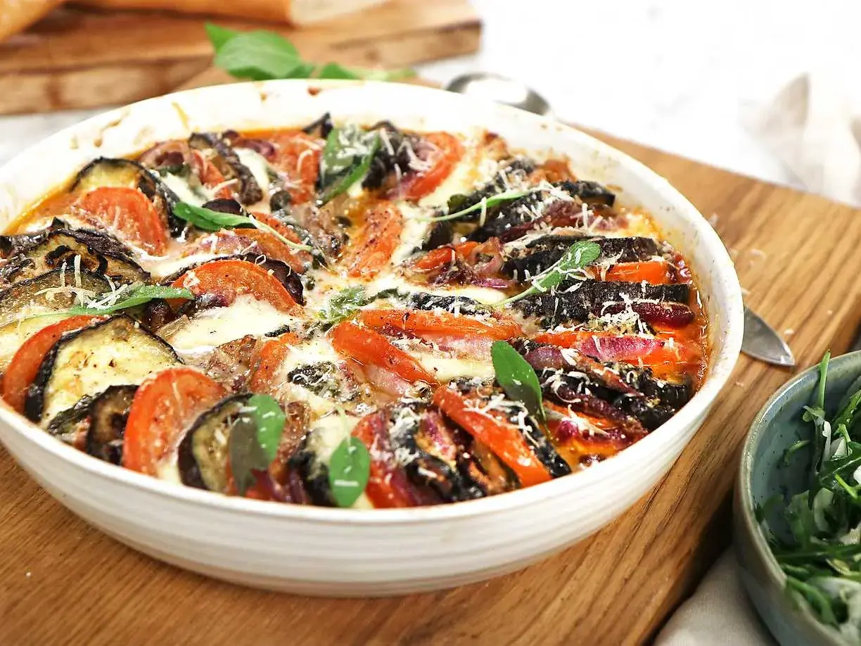 Gratinerad aubergine, tomat och mozzarella med färska örter. En härlig ugnsrätt som doftar sommar.