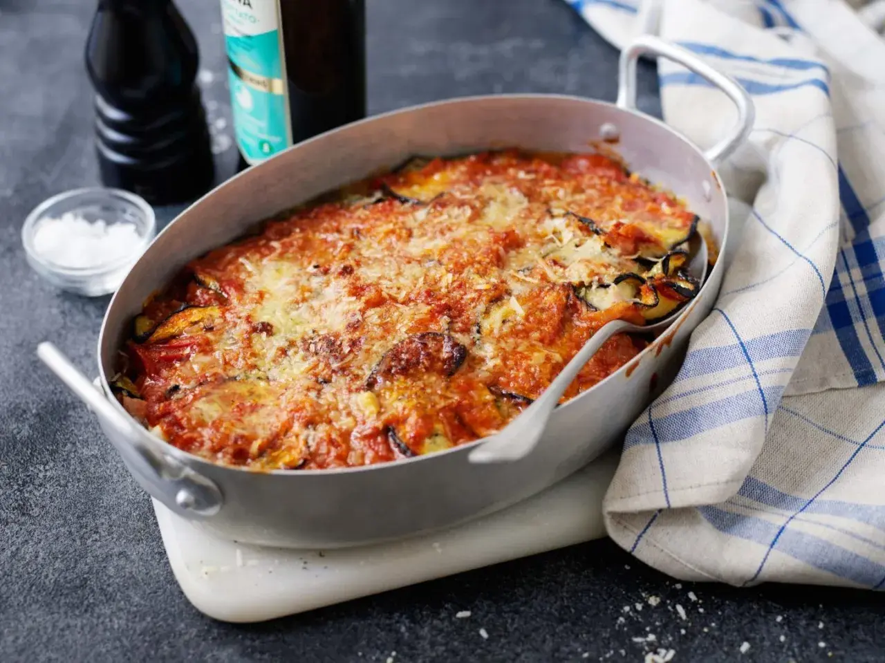 En ugnsform med en gyllene, bubblande melanzane alla parmigiana, toppad med smält ost och tomatsås.