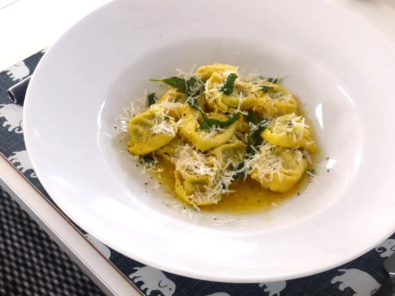 En tallrik med tortellini prosciutto, toppad med riven parmesan och färska örter.
