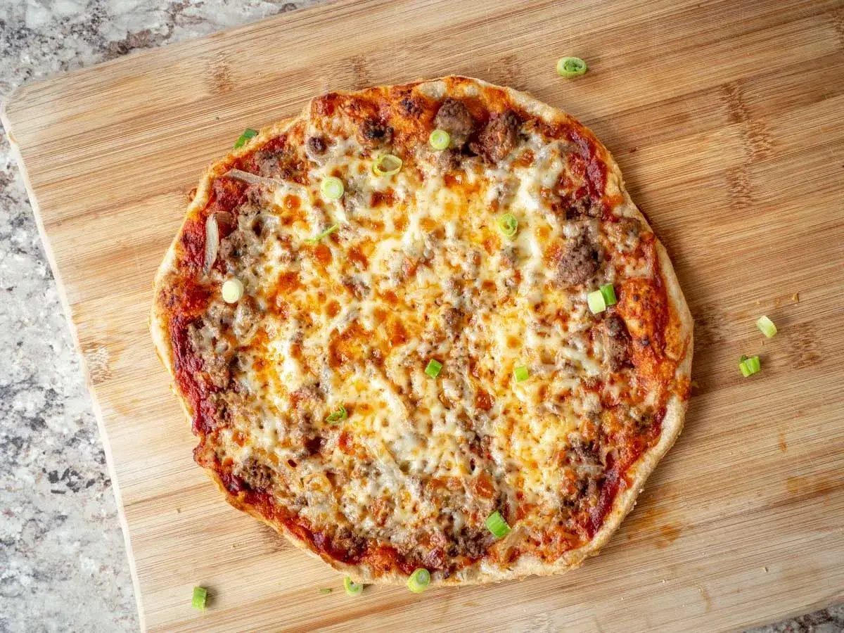 En saftig pizza med köttfärs och lök, toppad med smält ost och garnerad med färsk gräslök. Perfekt för en mysig kväll.