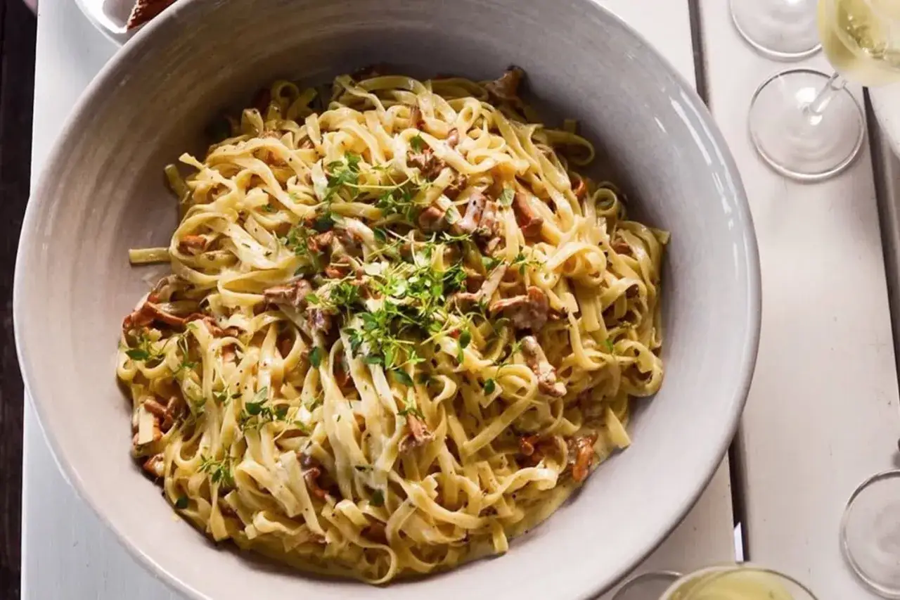 En stor skål med krämig kantarellpasta, toppad med färska örter. Perfekt för en höstmiddag.