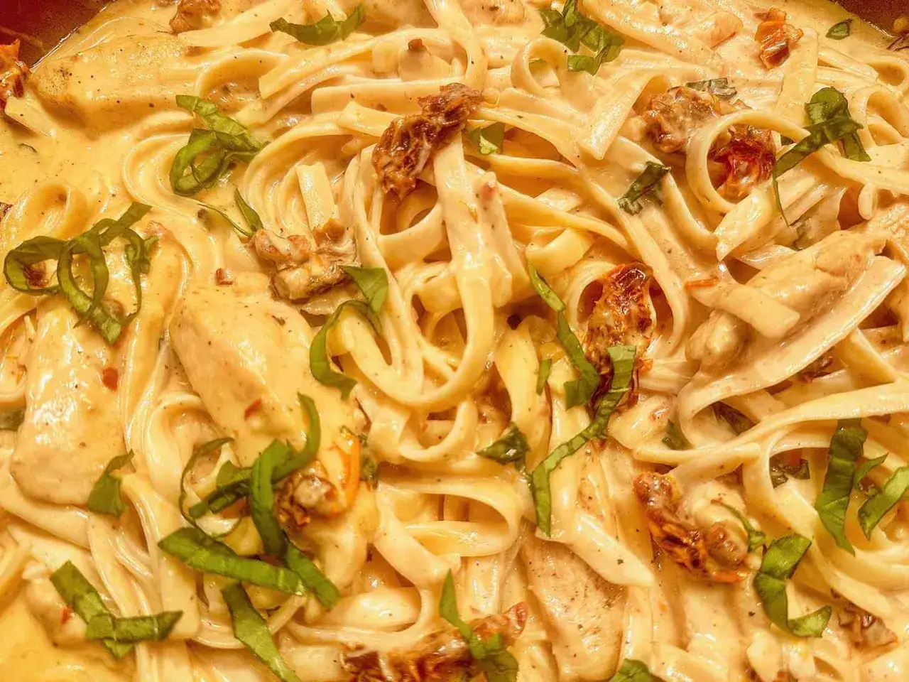 Krämig pasta med kyckling och soltorkade tomater, toppad med färsk basilika. En riktig smakupplevelse!