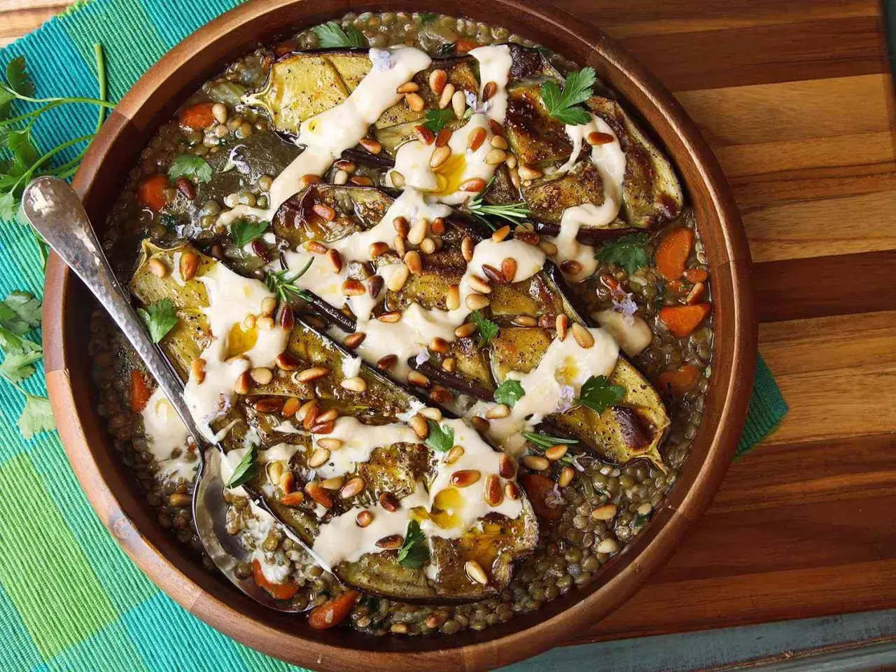 Ugnsbakad aubergine med linser, morötter och en krämig tahinisås, toppad med pinjenötter och färska örter. En härlig aubergine i ugn-rätt.