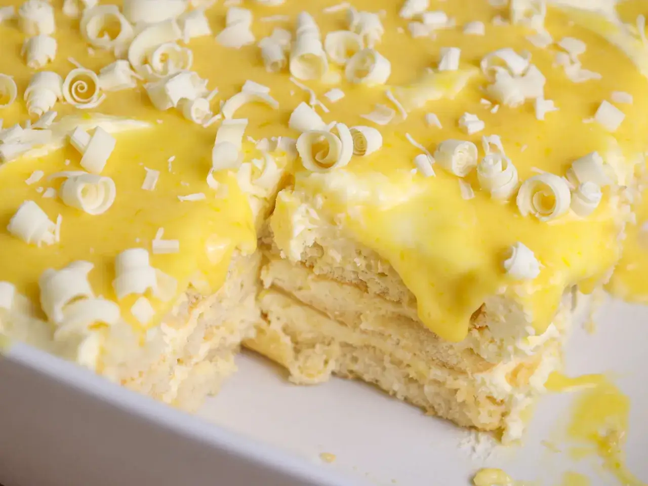 En krämig tiramisu limoncello med lager av savoiardikex och fluffig mascarponekräm, toppad med gul vaniljkräm och vita chokladlockar.