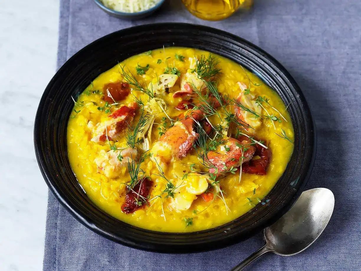 En krämig risotto milanese med hummerbitar, toppad med dill och soltorkade tomater.