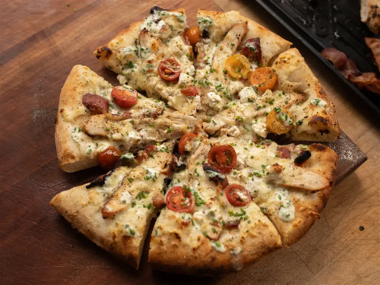 En saftig pizza med kyckling och bacon, toppad med körsbärstomater och krämig ost. En riktig smakupplevelse!