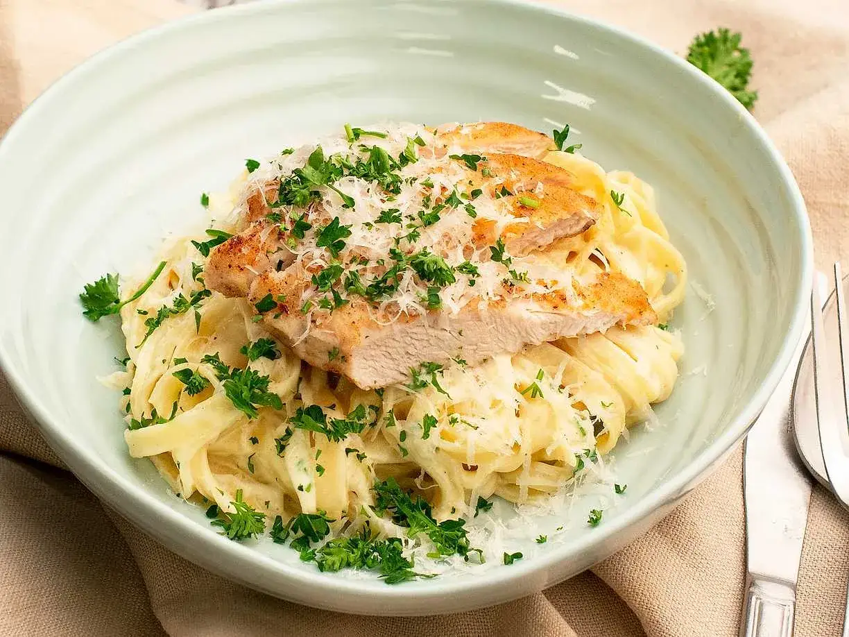 Krämig fettuccine med kyckling, toppad med parmesan och persilja. Ett perfekt fettuccine recept för en snabb middag.