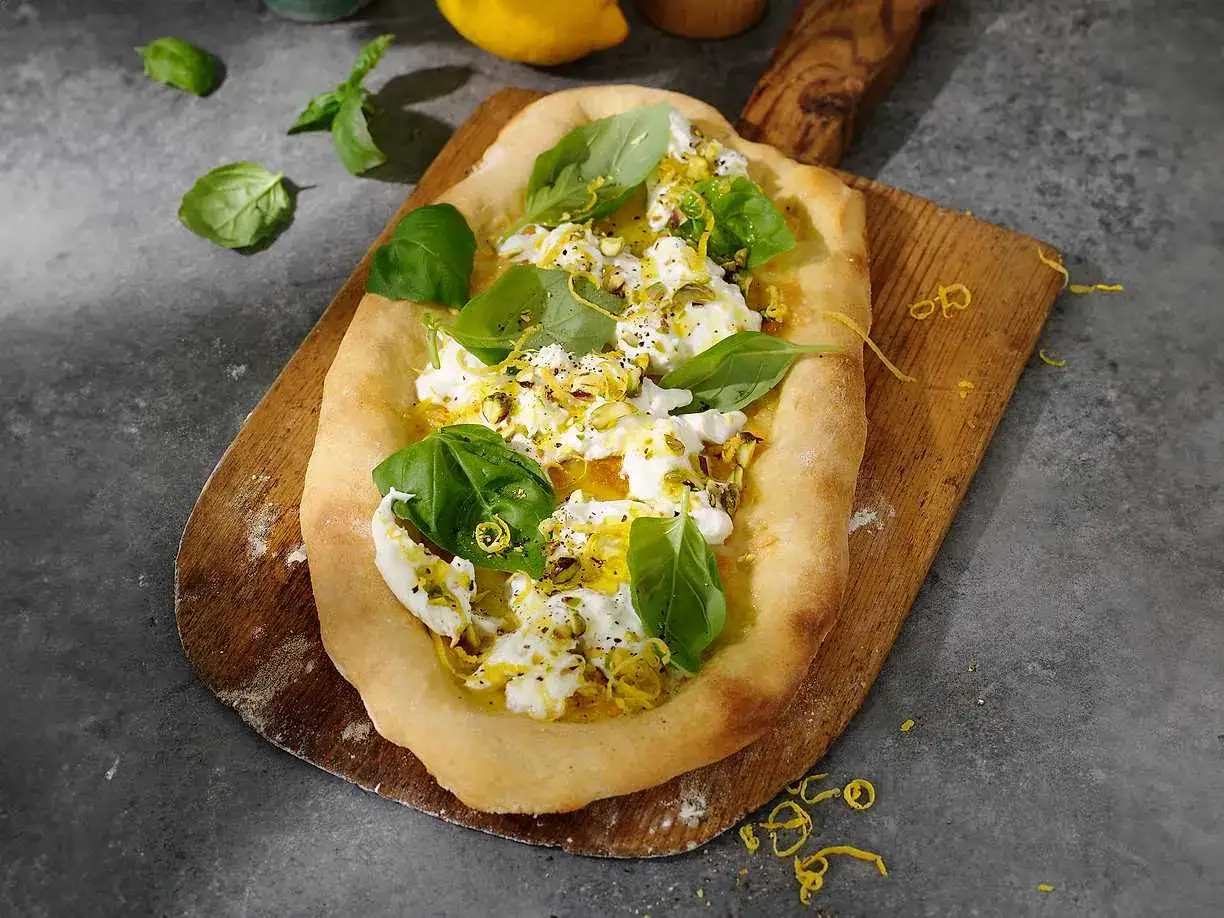 En pizza med krämig burrata, färsk basilika och citronskal. Ett perfekt burrata recept för en lätt lunch.