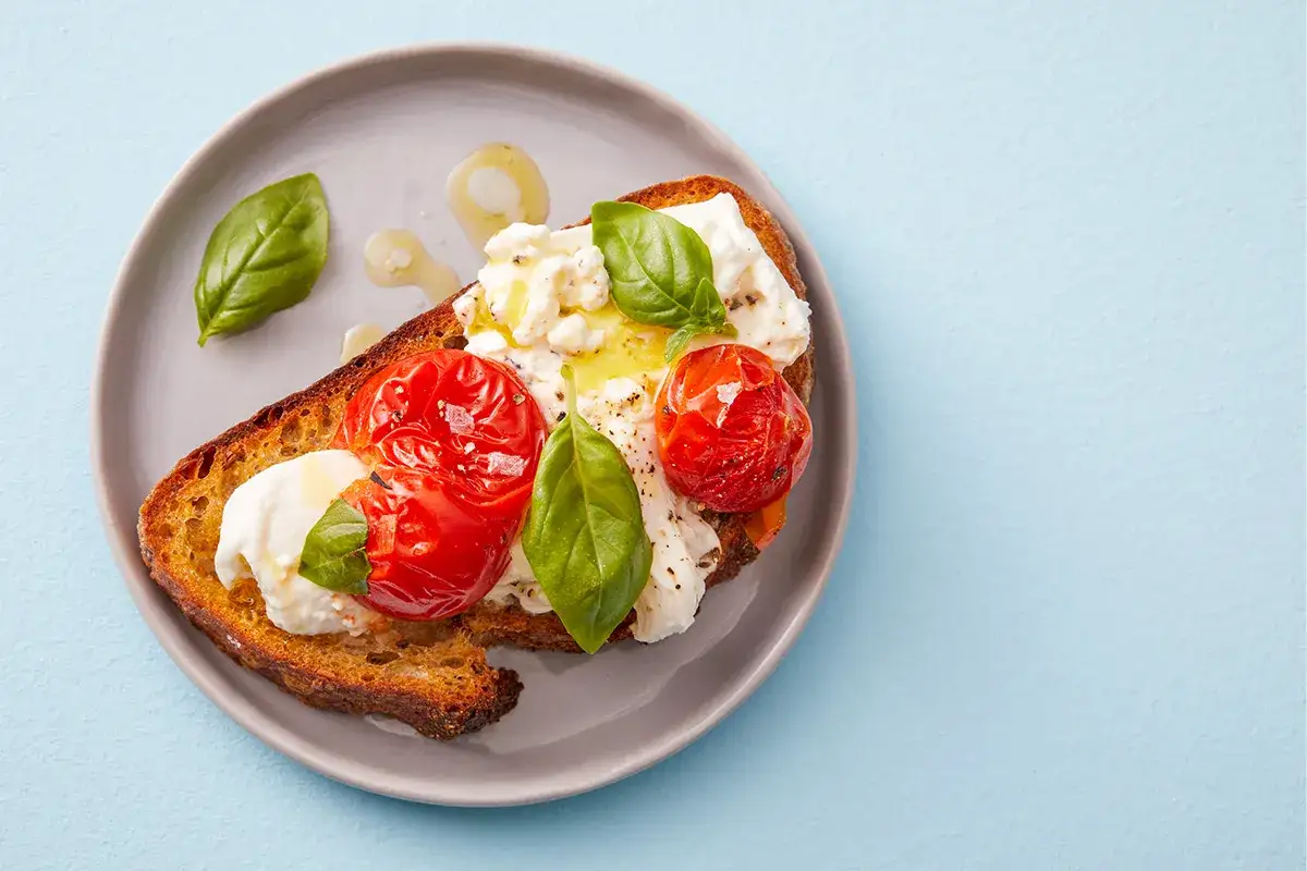 Rostat bröd med krämig stracciatella ost, ugnsbakade tomater och färsk basilika. Enkelt och gott!