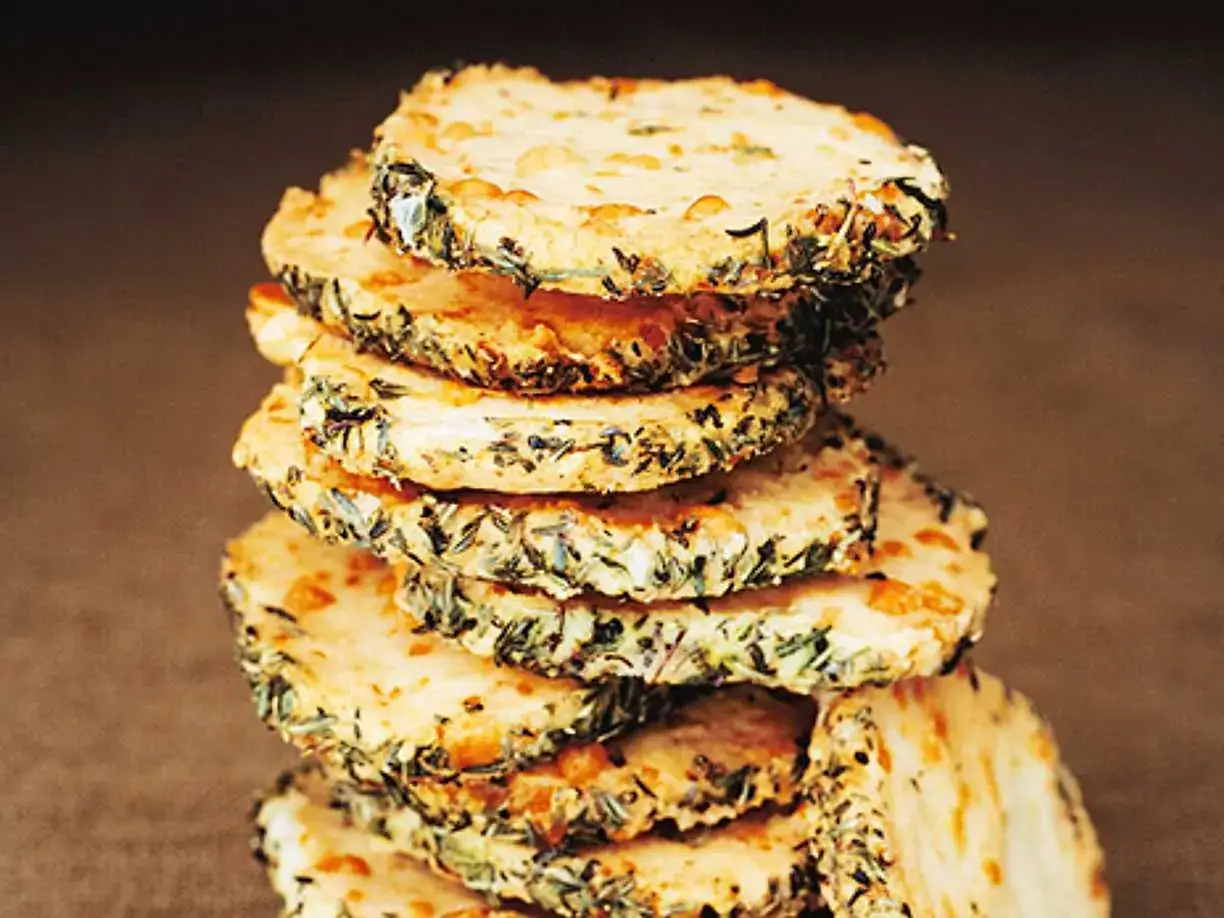 En stapel runda, gyllene parmesan kex med örter på kanten. Perfekta tilltugg!