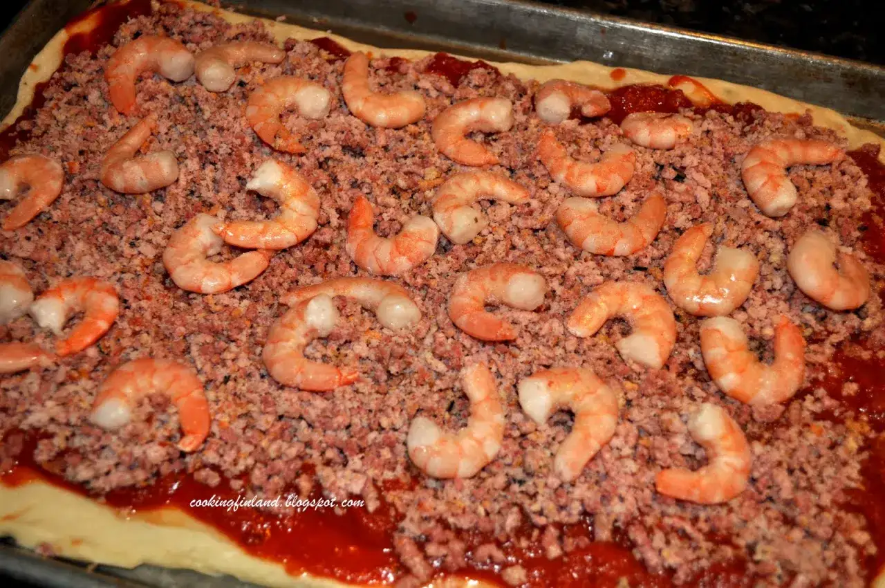 Pizza med räkor och skinka, redo att bakas. En härlig kombination av smaker som väntar på att avnjutas.