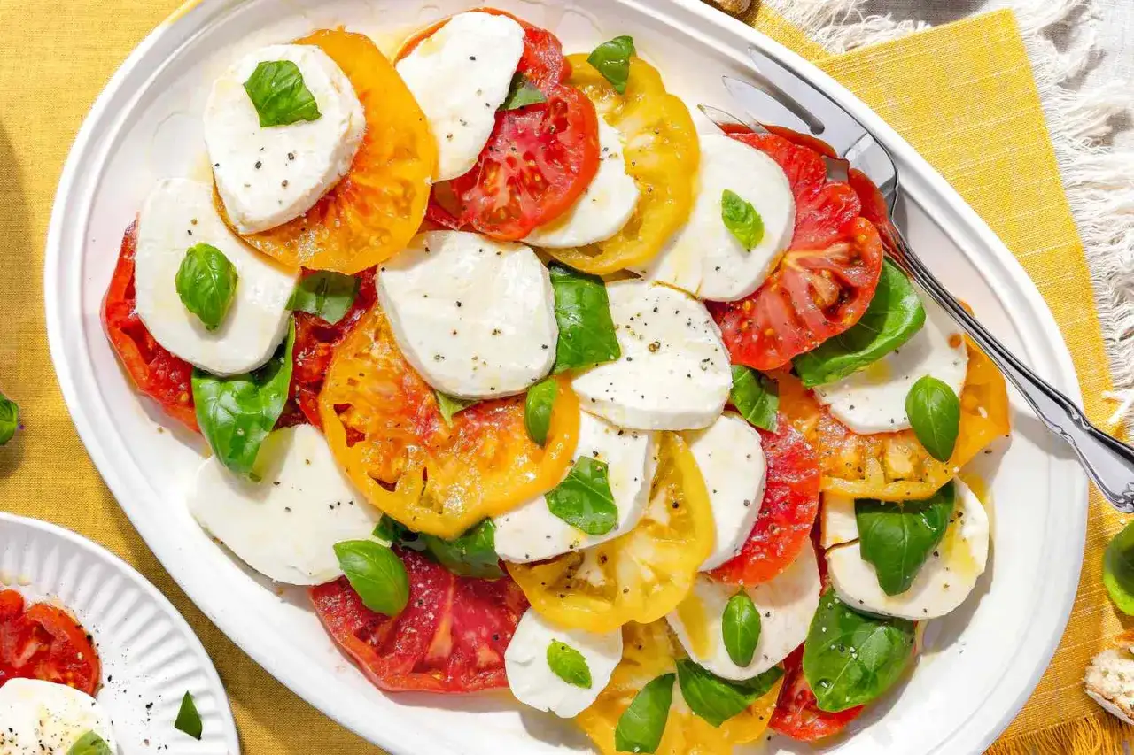 En vacker caprese med skivade tomater i olika färger, mozzarella och färsk basilika. Ett perfekt caprese recept för sommaren.