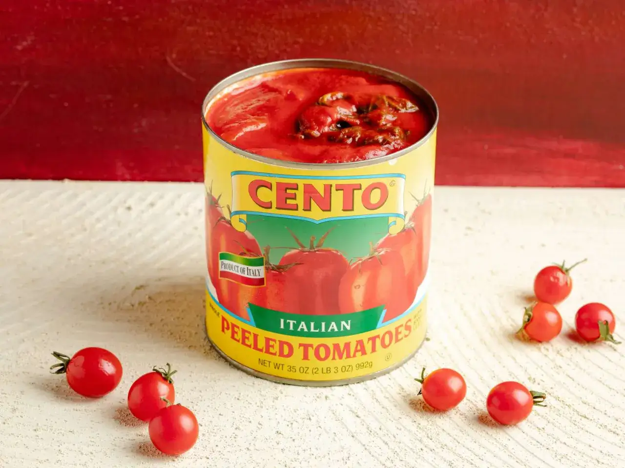 En burk med Cento krossade tomater, med några små tomater utspridda runt. Perfekt för en italiensk middag.