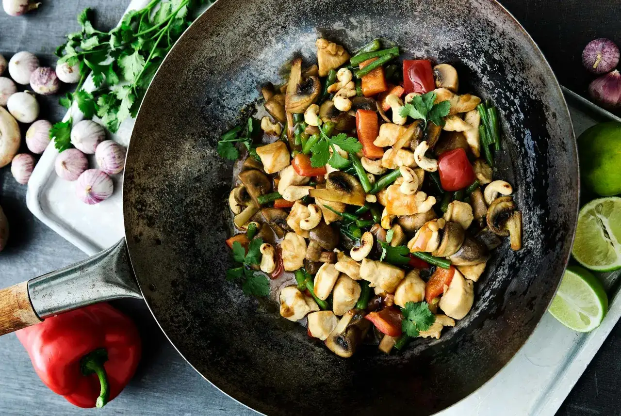 Kyckling och grönsaker som steks i olivolja i en wok. Svamp, paprika, cashewnötter och haricots verts blandas med saftiga kycklingbitar.