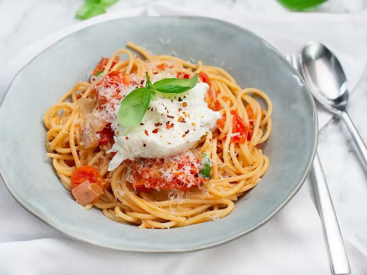 Spaghetti med tomatsås, toppad med krämig burrata och färsk basilika. Enkel och utsökt pasta burrata.