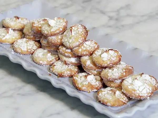 En hög med hembakade amaretti-kakor, pudrade med florsocker, redo att avnjutas. Ett enkelt amaretti recept.
