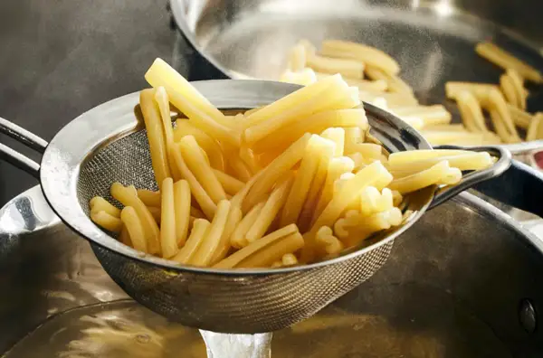 Nyskördade durumvete pasta i ett durkslag, redo att serveras.