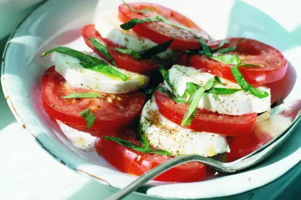 En klassisk napolitansk sallad med skivade tomater, färsk mozzarella och basilika, strödd med peppar. Enkel och fräsch.