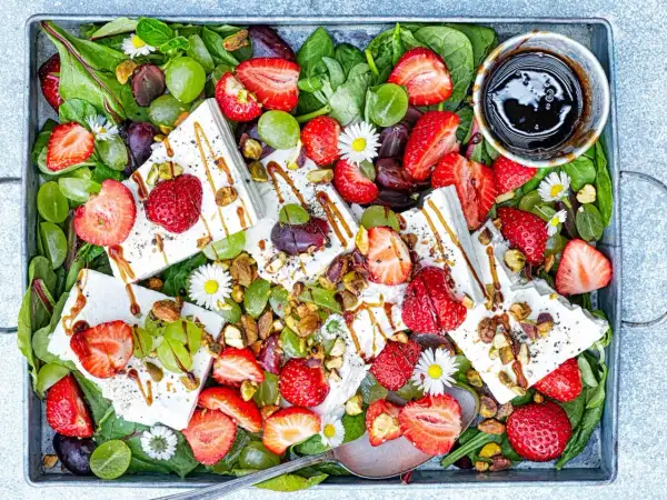 Sommarfräsch sallad med jordgubbar och fetaost, gröna druvor, nötter och en balsamico-dressing.