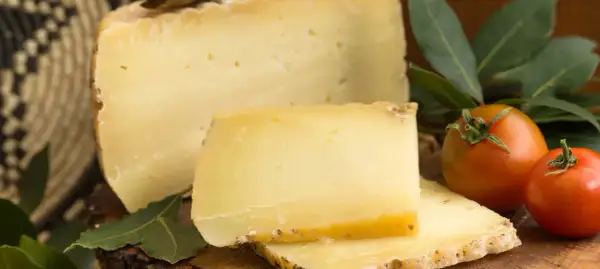 En bit pecorino ost med tomater och gröna blad.